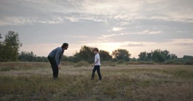 Man and Boy sahada koşuyor. Baba ve Çocuk Doğa 4K 10-bit 'te Birlikte Zaman Geçiriyorlar