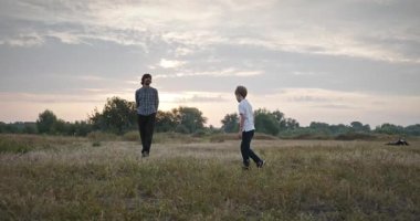 Man and Boy sahada koşuyor. Baba ve Çocuk Doğa 4K 10-bit 'te Birlikte Zaman Geçiriyorlar