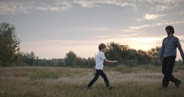 Man and Boy sahada koşuyor. Baba ve Çocuk Doğa 4K 10-bit 'te Birlikte Zaman Geçiriyorlar