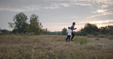 Man and Boy sahada koşuyor. Baba ve Çocuk Doğa 4K 10-bit 'te Birlikte Zaman Geçiriyorlar