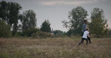 Man and Boy sahada koşuyor. Baba ve Çocuk Doğa 4K 10-bit 'te Birlikte Zaman Geçiriyorlar