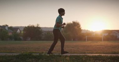 Futbol sahasında koşan çocuk. Çocuk Sabah Egzersizi Yapıyor Dışarıda 4K 10-bit Yavaş çekim 60 fps