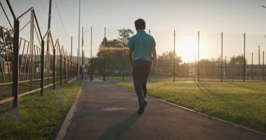 Futbol sahasında erkek yürüyüşü. Çocuk Sabah Egzersizi Yapıyor Dışarıda 4K 10-bit Yavaş çekim 60 fps