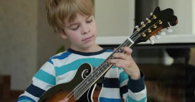 Beyaz çocuk evde Mandolin oynuyor. Avrupalı Çocuk Müzik Çalışması 4K 10-bit