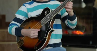 Beyaz çocuk evde Mandolin oynuyor. Avrupalı Çocuk Müzik Çalışması 4K 10-bit