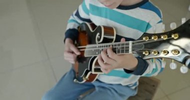 Beyaz çocuk evde Mandolin oynuyor. Avrupalı Çocuk Müzik Çalışması 4K 10-bit