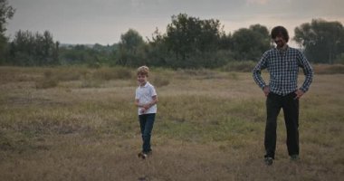 Adam ve Çocuk Sahada Konuşuyor. Baba ve Çocuk Doğa 4K 10-bit 'te Birlikte Zaman Geçiriyorlar