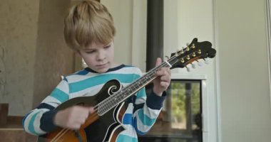 Beyaz çocuk evde Mandolin oynuyor. Avrupalı Çocuk Müzik Çalışması 4K 10-bit