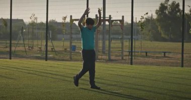 Çocuk futbol sahasında antrenman yapıyor. Çocuk Sabah Egzersizi Yapıyor Dışarıda 4K 10-bit Yavaş çekim 60 fps