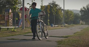 Futbol sahasının yanında bisikletli çocuk yürüyüşü. 4K 10-bit.