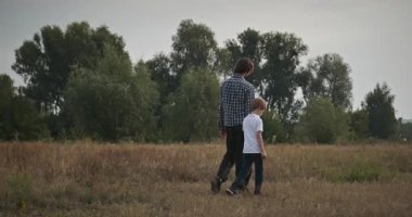 Adam ve Çocuk Sahada Konuşuyor. Baba ve Çocuk Doğa 4K 10-bit 'te Birlikte Zaman Geçiriyorlar