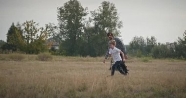 Man and Boy sahada koşuyor. Baba ve Çocuk Doğa 4K 10-bit 'te Birlikte Zaman Geçiriyorlar