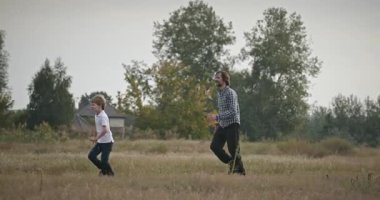 Man and Boy sahada koşuyor. Baba ve Çocuk Doğa 4K 10-bit 'te Birlikte Zaman Geçiriyorlar