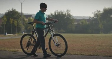 Futbol sahasının yanında bisikletli çocuk yürüyüşü. 4K 10-bit.