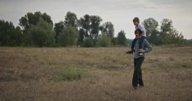 Mutlu Adam, çocuğu omuzlarında taşıyor. Baba ve Çocuk Doğa 4K 10-bit 'te Birlikte Zaman Geçiriyorlar