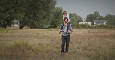 Mutlu Adam, çocuğu omuzlarında taşıyor. Baba ve Çocuk Doğa 4K 10-bit 'te Birlikte Zaman Geçiriyorlar