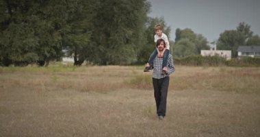 Mutlu Adam, çocuğu omuzlarında taşıyor. Baba ve Çocuk Doğa 4K 10-bit 'te Birlikte Zaman Geçiriyorlar