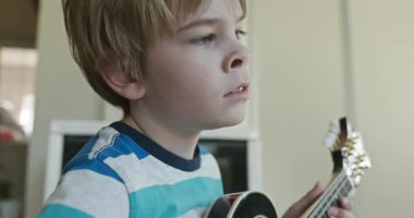Beyaz çocuk evde Mandolin oynuyor. Avrupalı Çocuk Müzik Çalışması 4K 10-bit