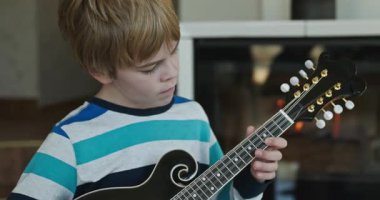 Beyaz çocuk evde Mandolin oynuyor. Avrupalı Çocuk Müzik Çalışması 4K 10-bit