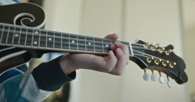 Beyaz çocuk evde Mandolin oynuyor. Avrupalı Çocuk Müzik Çalışması 4K 10-bit
