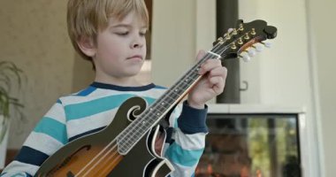 Beyaz çocuk evde Mandolin oynuyor. Avrupalı Çocuk Müzik Çalışması 4K 10-bit