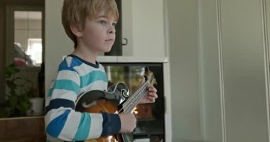 Beyaz çocuk evde Mandolin oynuyor. Avrupalı Çocuk Müzik Çalışması 4K 10-bit