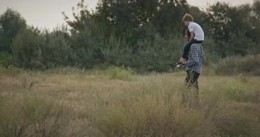 Mutlu Adam, çocuğu omuzlarında taşıyor. Baba ve Çocuk Doğa 4K 10-bit 'te Birlikte Zaman Geçiriyorlar