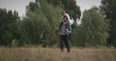 Mutlu Adam, çocuğu omuzlarında taşıyor. Baba ve Çocuk Doğa 4K 10-bit 'te Birlikte Zaman Geçiriyorlar