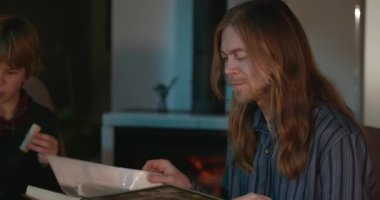 Çocuk, amcası ve babasıyla birlikte müzik dinleyip 4K 10-bit 'lik aile albümü izliyor.