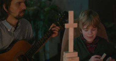 Çocuk, amcası ve babasıyla birlikte müzik dinleyip 4K 10-bit 'lik aile albümü izliyor.