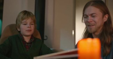 Amcası ve babası olan bir çocuk heyecanlı bir kitap okuyor. 4K 10-bit eğleniyor.