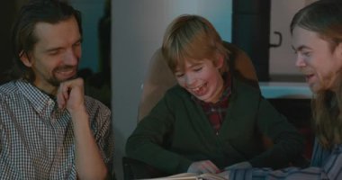 Amcası ve babası olan bir çocuk heyecanlı bir kitap okuyor. 4K 10-bit eğleniyor.