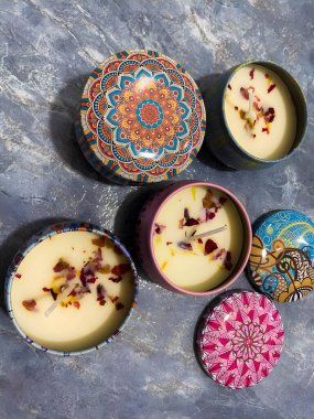 Metal tutacaklardaki mumlar etnik desenli, balmumunda çiçek yaprakları olan. Mumlar beyaz arkaplanda. Kapaklı mumlar.