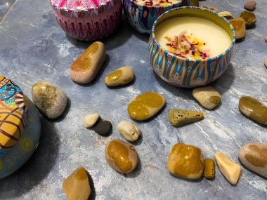 Metal tutacaklardaki mumlar etnik desenli, balmumunda çiçek yaprakları olan. Mumlar beyaz arkaplanda. Kapaklı mumlar.