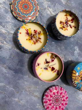 Metal tutacaklardaki mumlar etnik desenli, balmumunda çiçek yaprakları olan. Mumlar beyaz arkaplanda. Kapaklı mumlar.