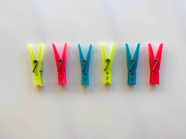 Çamaşırları dışarı asmak için plastik renkli mandallar. Plaj havlusu mandalları, havlu tutacağı, plastik giysi askıları, askı tutacağı, kıskaçlar, mandallar. Beyaz arkaplanda