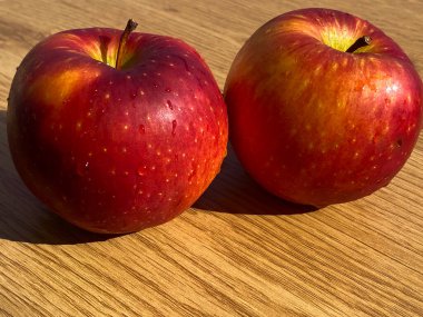 Ahşap masada iki kırmızı elma. Ahşap zemin, su damlaları