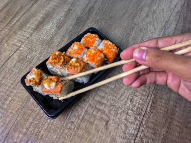 Geleneksel suşi yemeye hazır yemek çubuklarını tutan ellerin yakın çekimi..