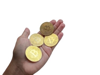 Bu resim, modern finans sektöründe kripto para biriminin yükselişini temsil eden birkaç Bitcoin sikkesi gösteren bir el gösteriyor..
