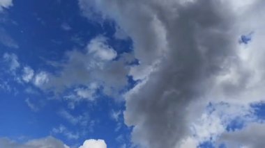 Kabarık bulutların dinamik hareketi canlı mavi bir gökyüzü boyunca.