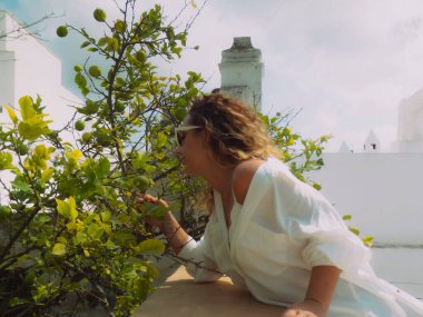 Bir kadın terasındaki bir ağacın yapraklarına dokunur.