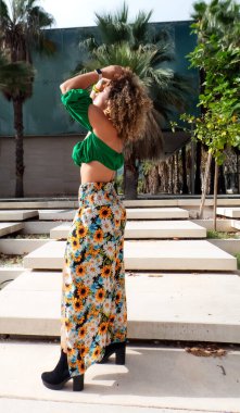 Afro-Amerikan bir kızın parkta yürürken güneşlenirken çekilmiş dikey fotoğrafı.