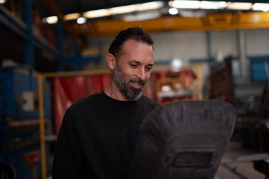 Kaynak işinde çalışan adam koruyucu kaynak maskesi takıyor.