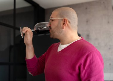 Pembe kazaklı bir adam arkadaşlarıyla bir partide şarap içiyor.