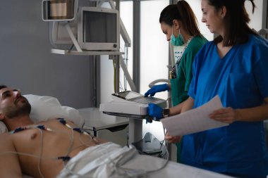 Yoğun bakımdaki bir hastaya elektrokardiyogram yapan hemşireler.