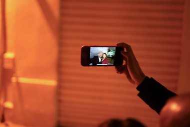 El ele tutuşan cep telefonunda zarif bir çiftin bir resim için poz verirken çekilmiş fotoğrafı var.