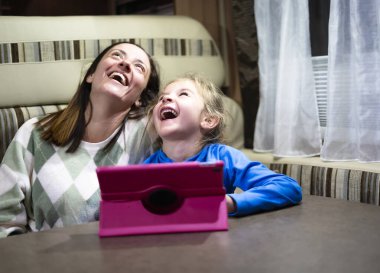 Anne ve kızı bir karavanda tabletten komik bir video izlerken gülüyorlar.