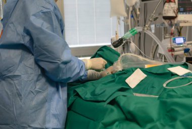 Cerrah, hastane ameliyathanesinde cerrahi bir işlem sırasında hastaya ilaç enjekte ediyor.