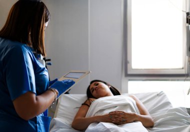 Hastane odasındaki hasta kayıtlarını kontrol etmek için tablet teknolojisi kullanan hemşire.