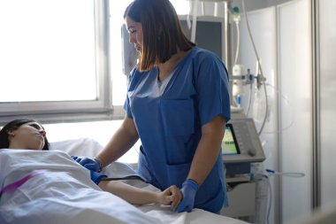 Hemşire hastayla ilgileniyor ve hastane odasında kan basıncını ölçüyor.